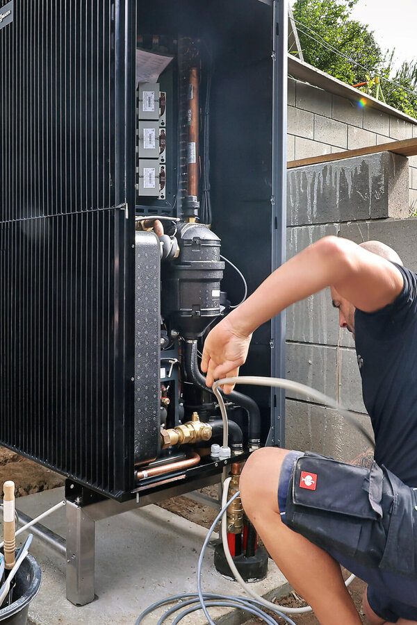 Techniker wartet Wärmepumpe am Haus